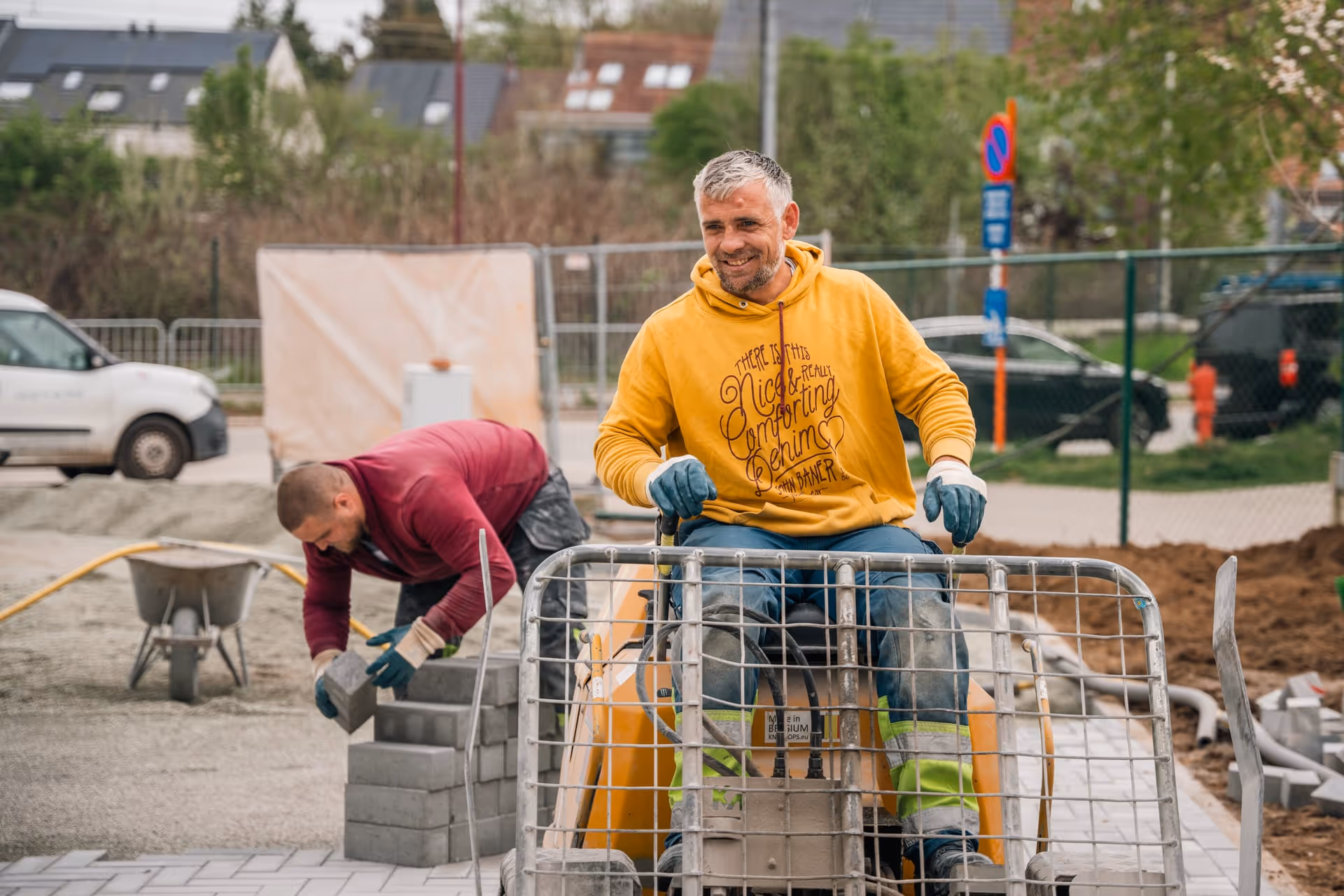 Twee bouwvakkers: de ene bedient machines en de andere stapelt stenen op een bouwplaats.