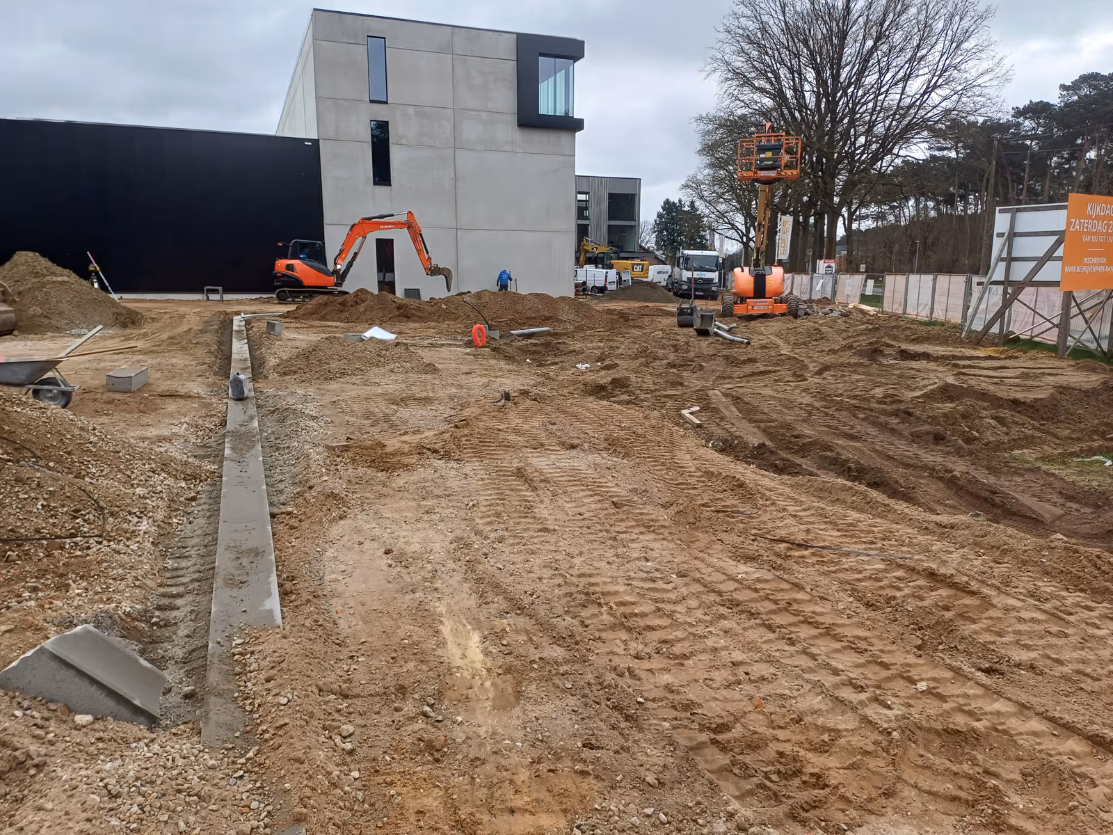 Een bouwplaats met grondwerken; opgegraven grond voor een modern betonnen gebouw.
