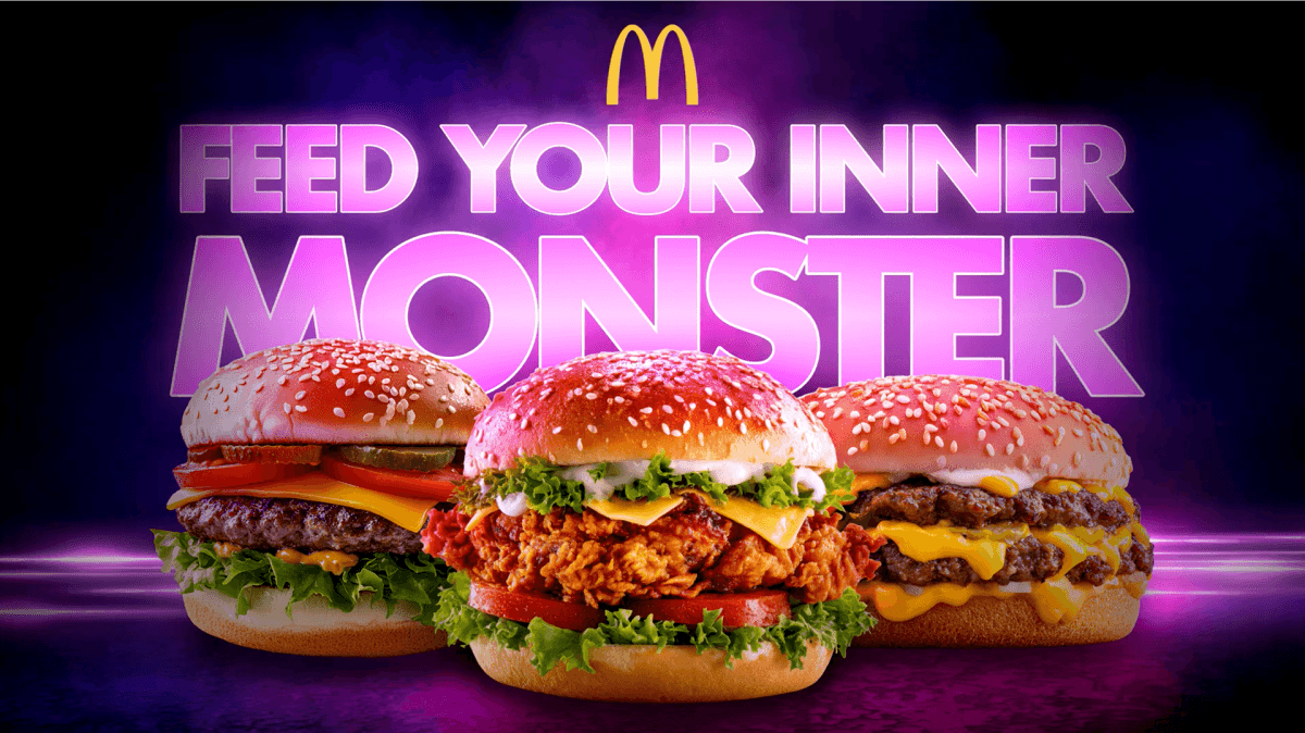 Three McDonald’s Monster Burgers in front of purple glowing text reading 'FEED YOUR INNER MONSTER' with the McDonald's golden arches logo above.