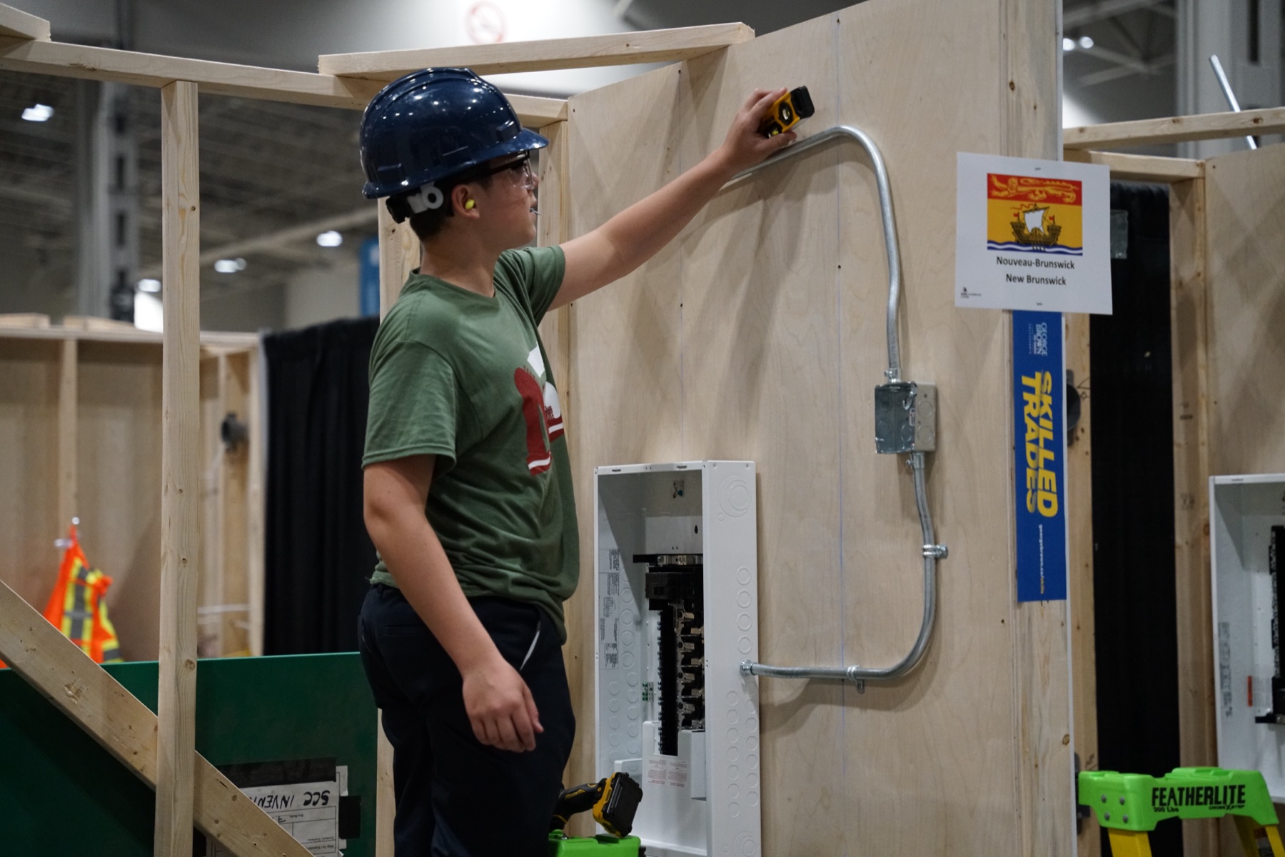 Electrical competitor bending conduit on a wall panel at a skilled trades competition