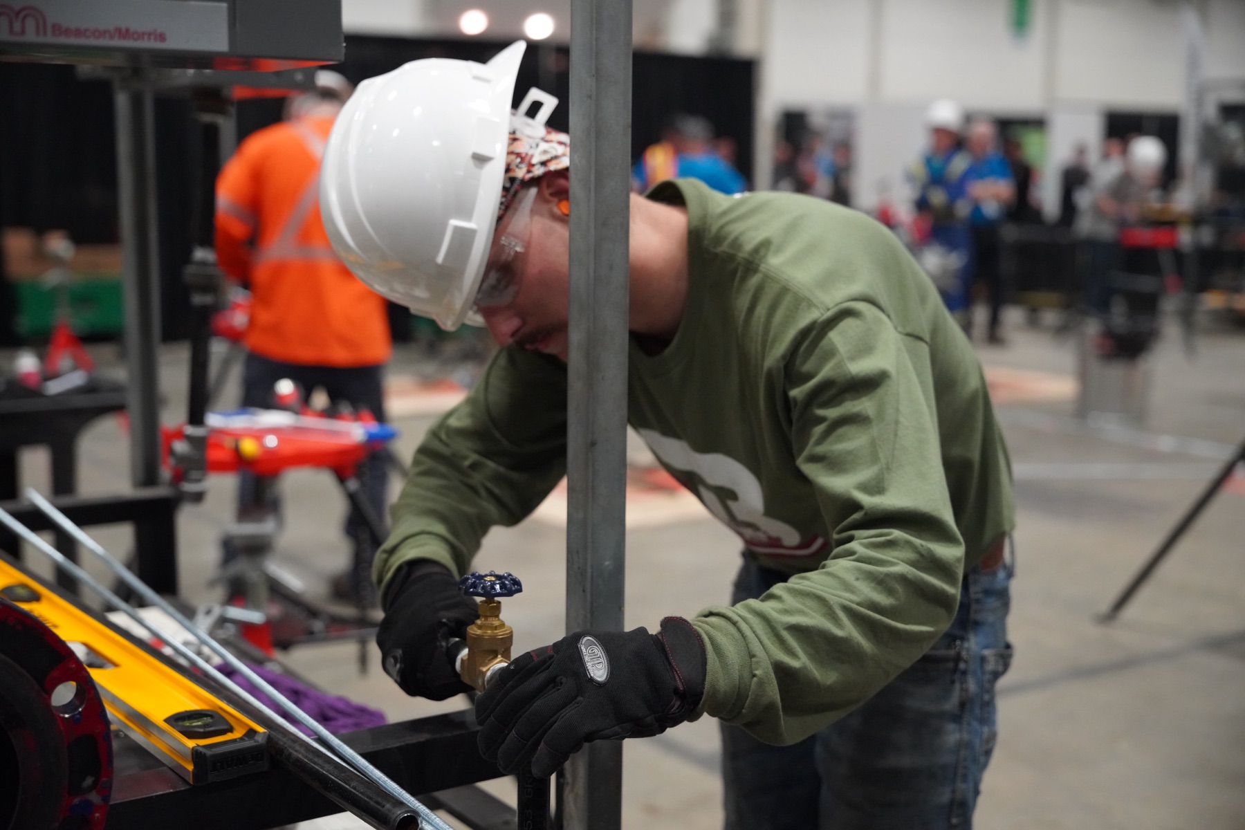 Competitor in a white hard hat working with metal at a skilled trades competition