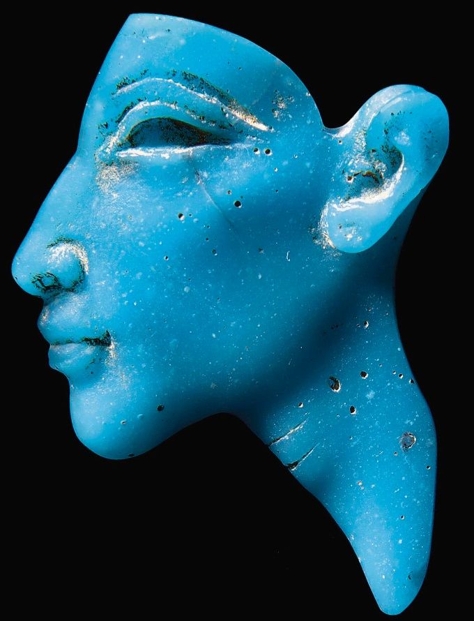 Blue ancient Egyptian-style carved face in profile with detailed eye, nose, lips, and ear set against a black background.