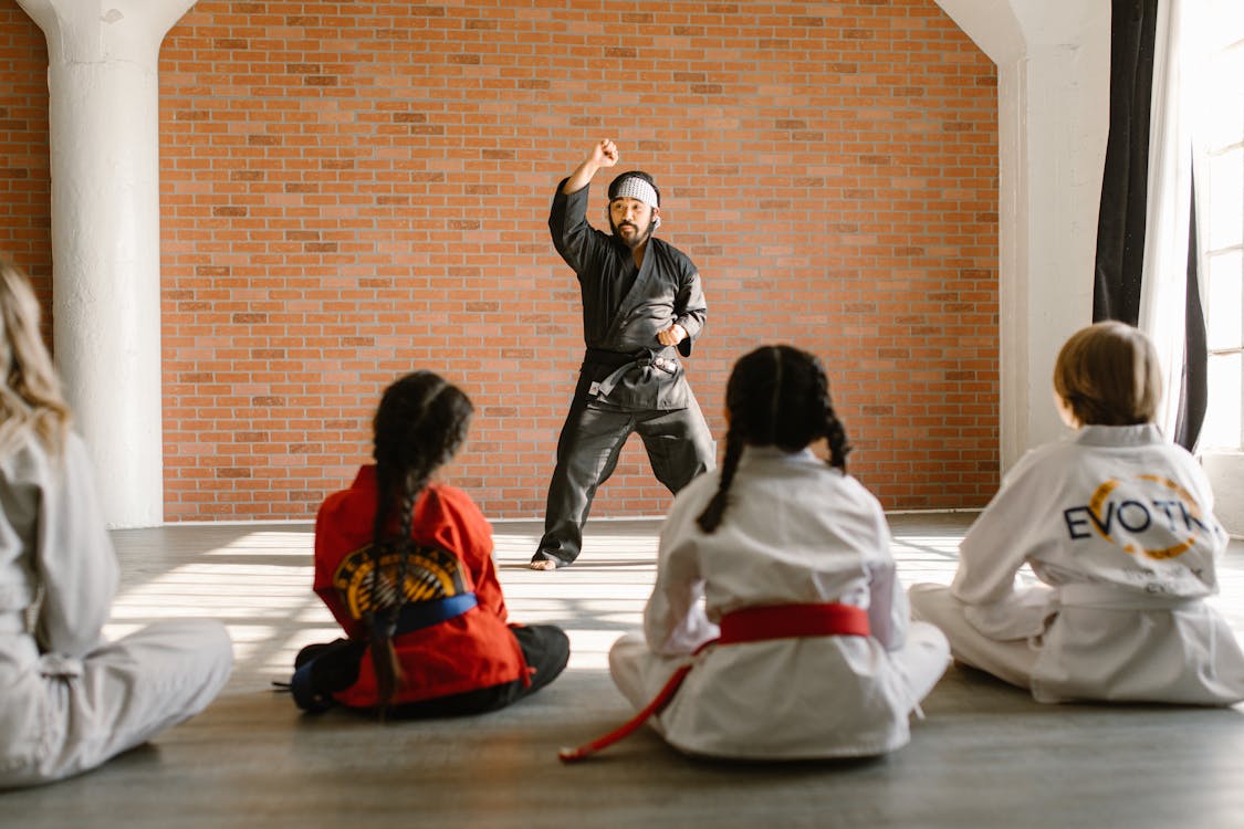 Martial arts instructor demonstrating technique to a group of attentive young students in a modern dojo