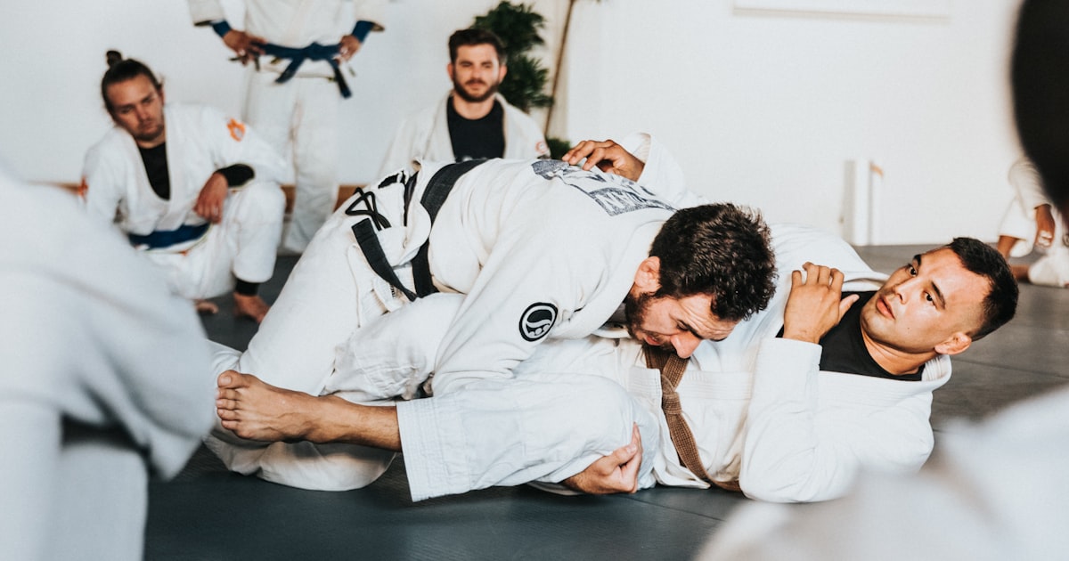 Martial arts practitioners with different belt ranks training together on the dojo mat
