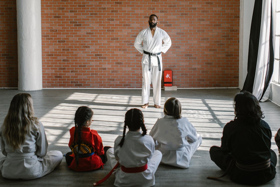 Young martial arts students in white gis learning from a black belt instructor in a traditional dojo