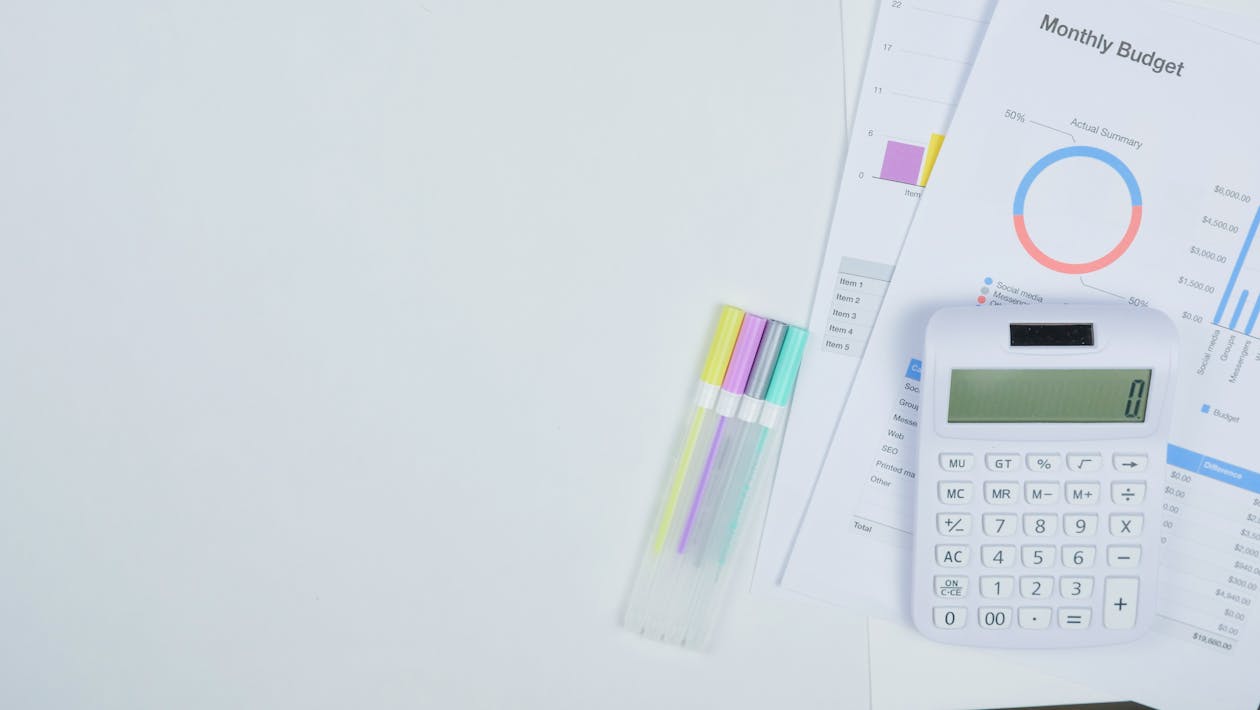 A calculator and budget planning documents on a desk, representing the cost analysis a dojo owner should perform when comparing management software