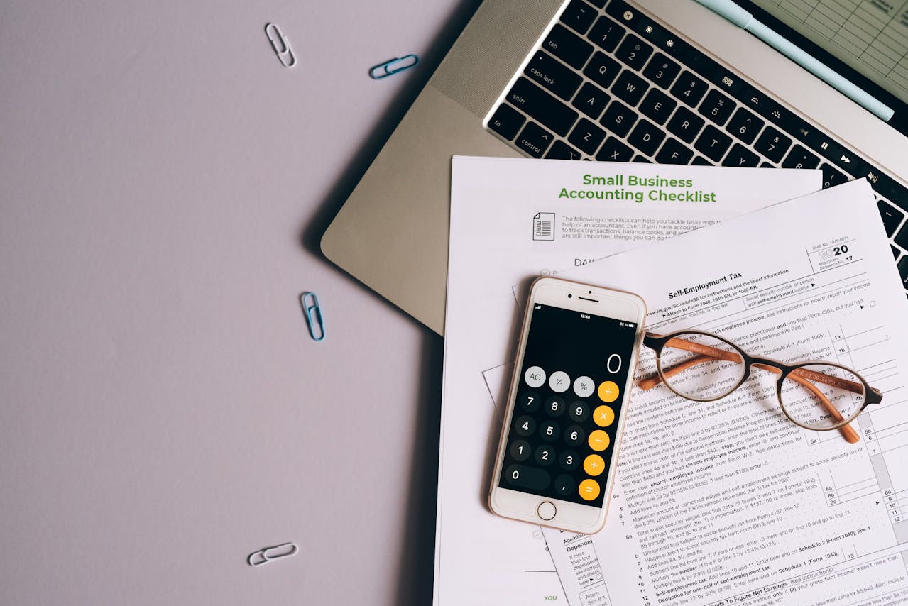 Accountant desk with calculator, glasses, and financial documents representing the small business financial planning every dojo owner must do