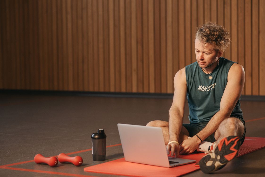 A martial arts instructor on a studio mat comparing dojo management software on a laptop