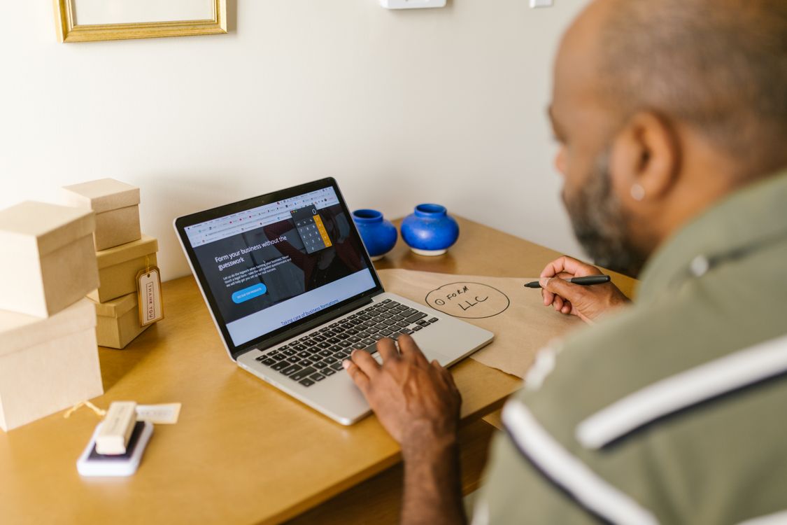 A small business owner at a desk working through paperwork and admin on a laptop