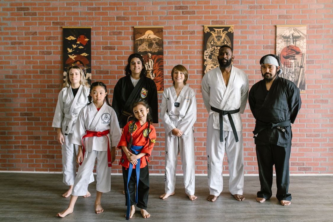 Martial artists of different ages, from children to adults, standing together in a dojo, the mixed-age room a tap-based check-in has to work for