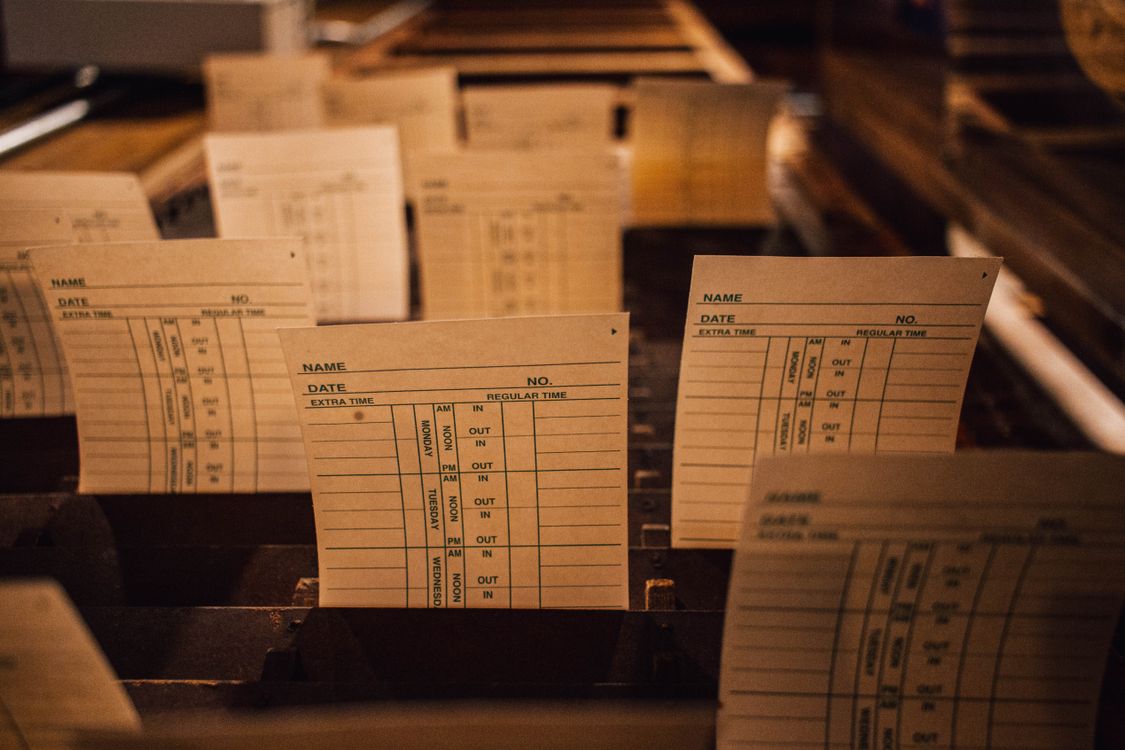 Rows of paper time cards standing in a wooden rack, the low-tech way schools have logged attendance for decades