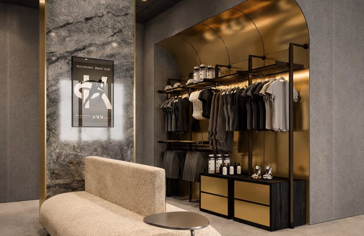 Nowoczesny butik z beżową sofą, ścianą marmurową i metalowymi półkami z różnymi ciemnymi i jasnymi ubraniami.