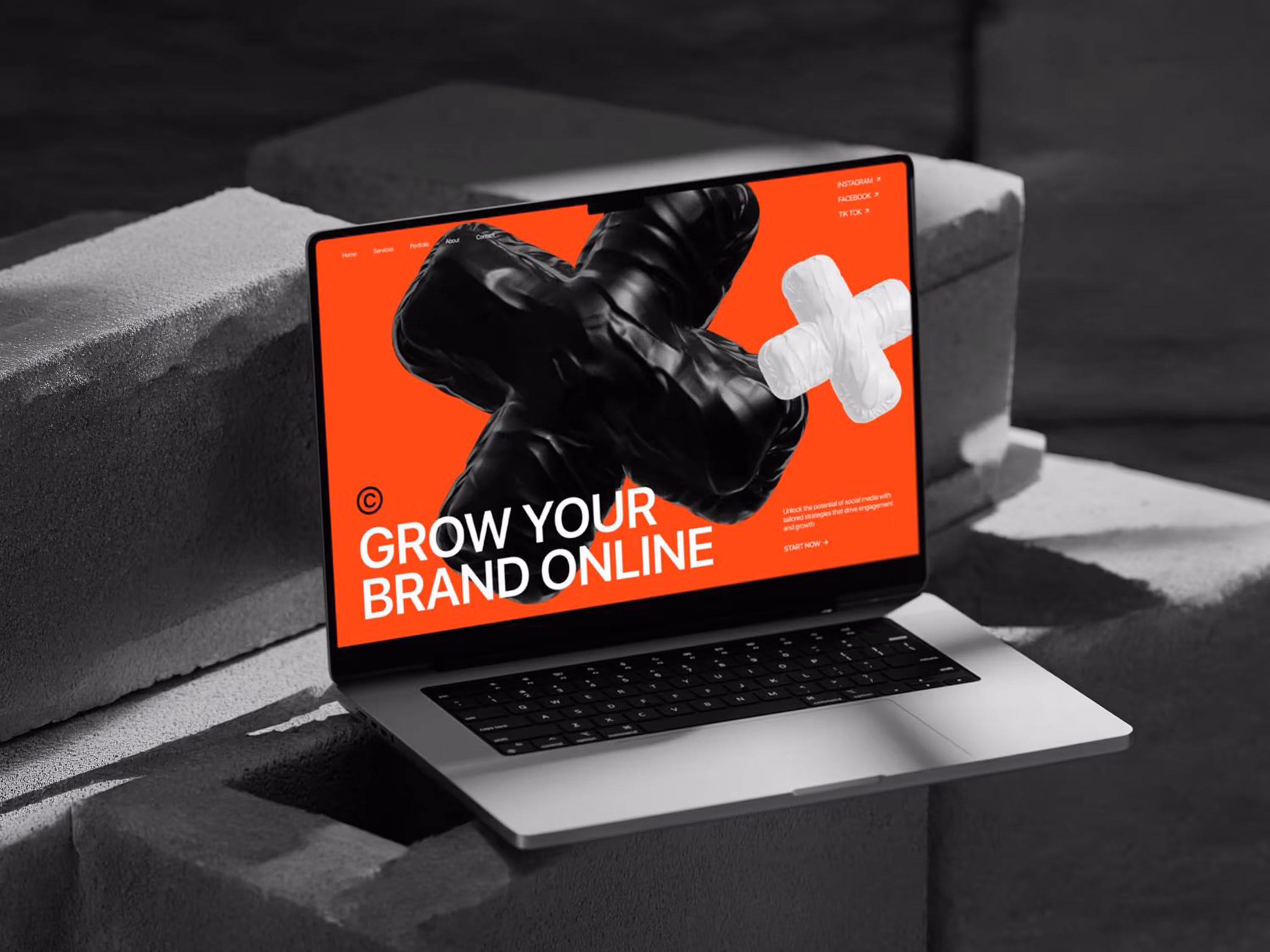 Laptop pe blocuri de beton afisand un design web cu accente rosii