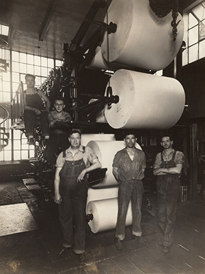 old photo of newspaper press workers in front of large printing presses
