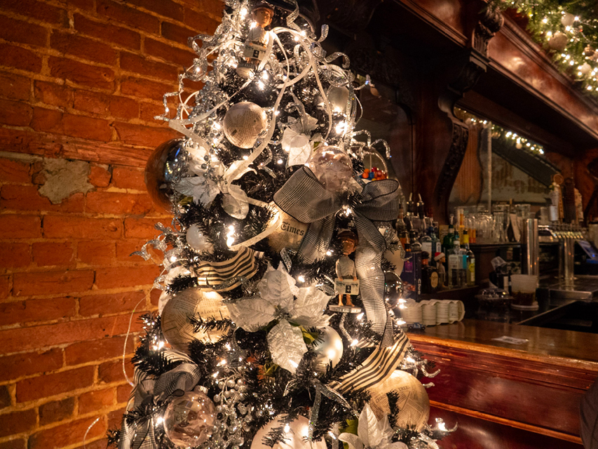 A newspaper-themes Christmas tree next to a bar