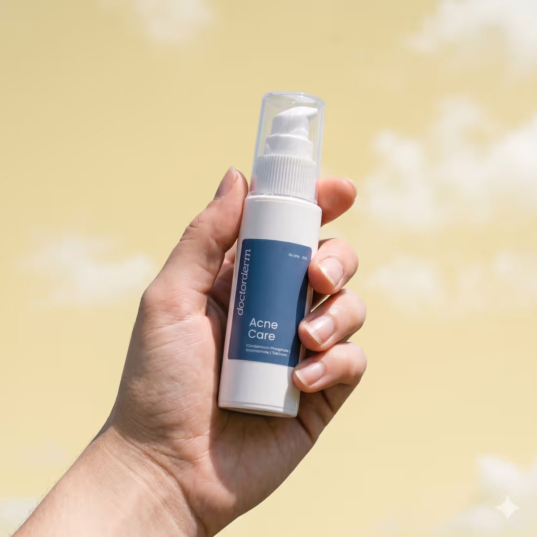 A hand holding DoctorDerm Acne Care against a yellow sky