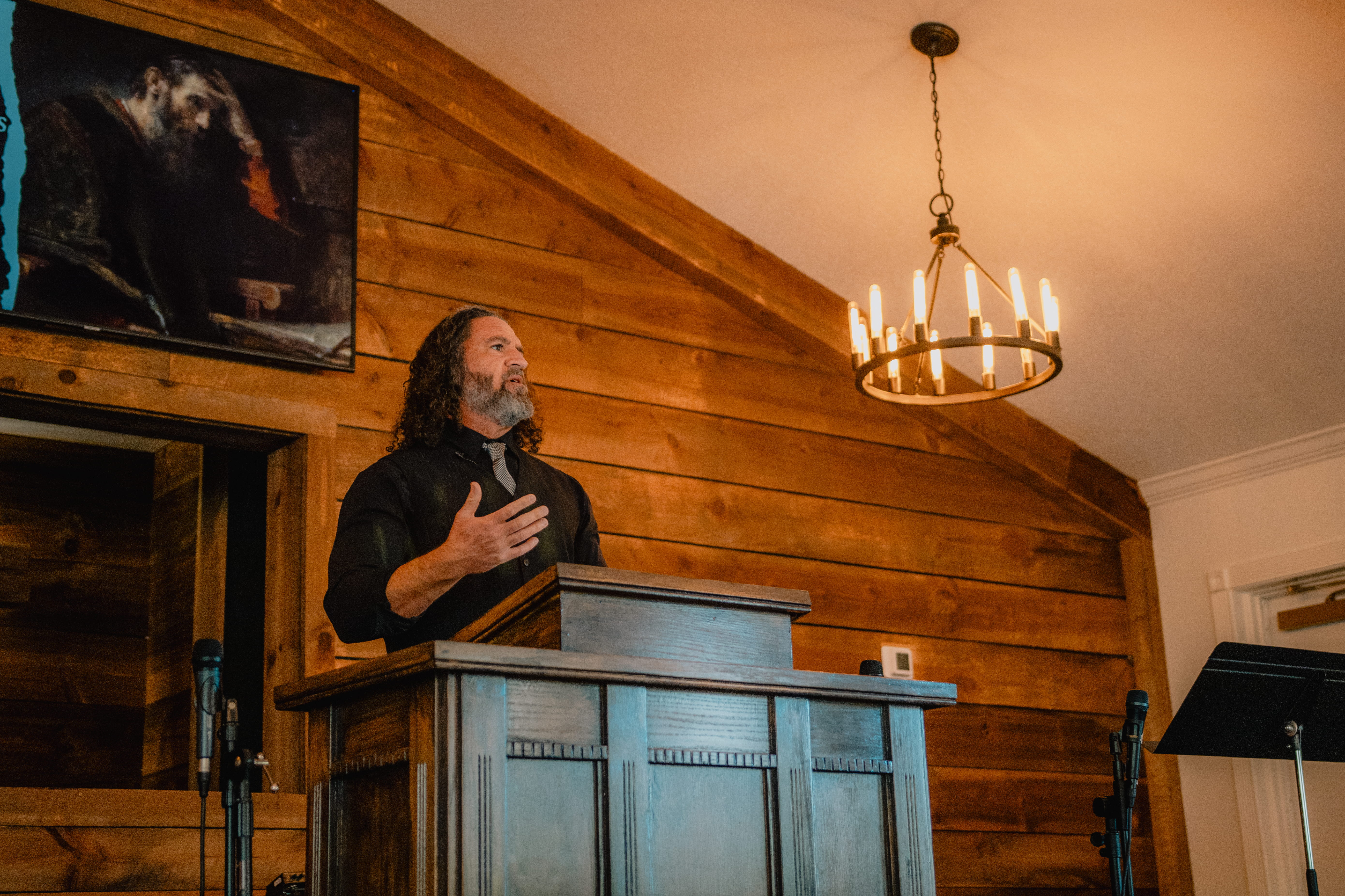 Pastor Britt Wattson speaking at wooden podium in the main sanctuary of Christ Reformed Church