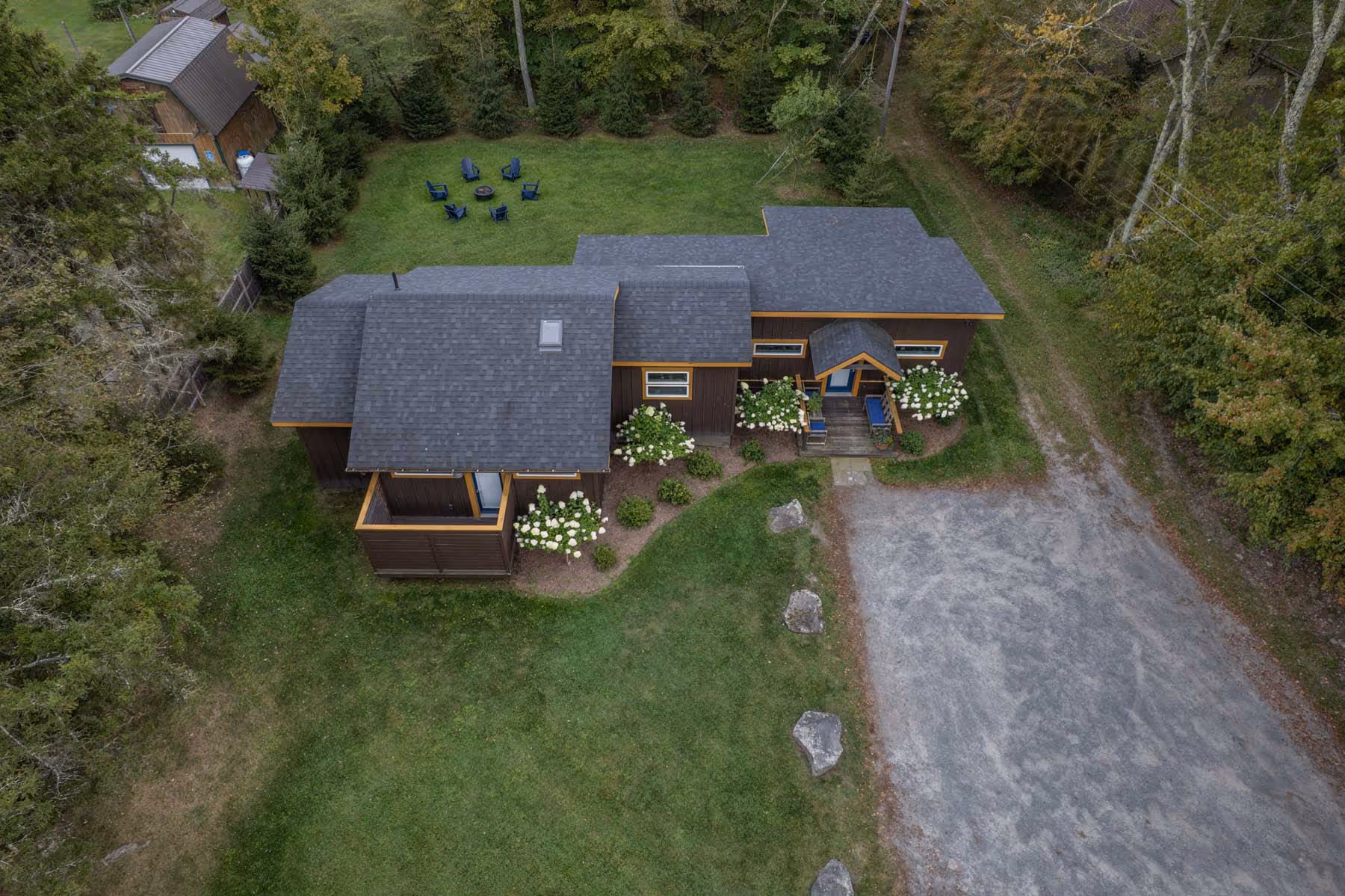 Aerial view of a modern house with gray roof, surrounded by green lawn and trees.