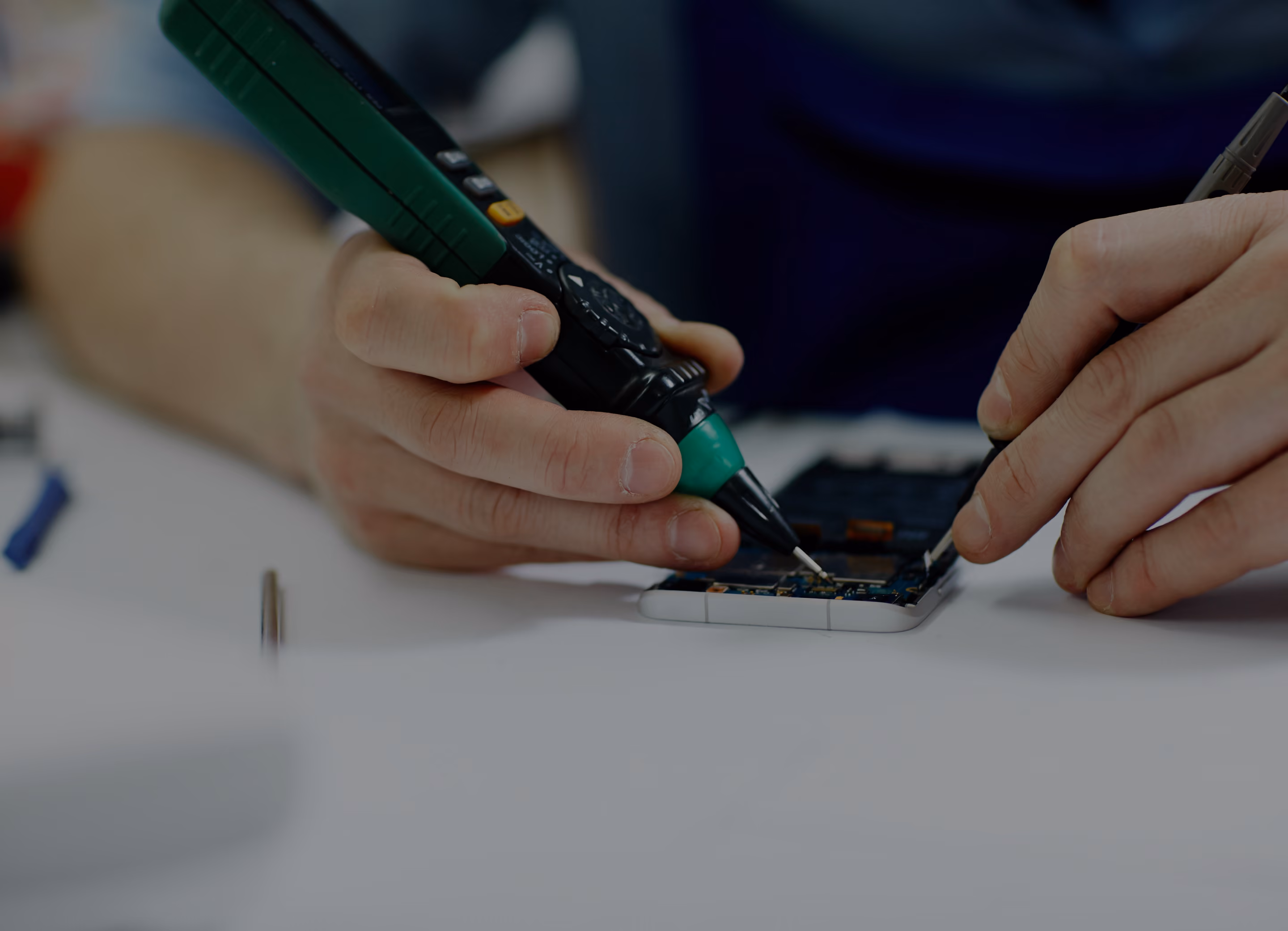 Technician testing a phone logic board with a multimeter probe