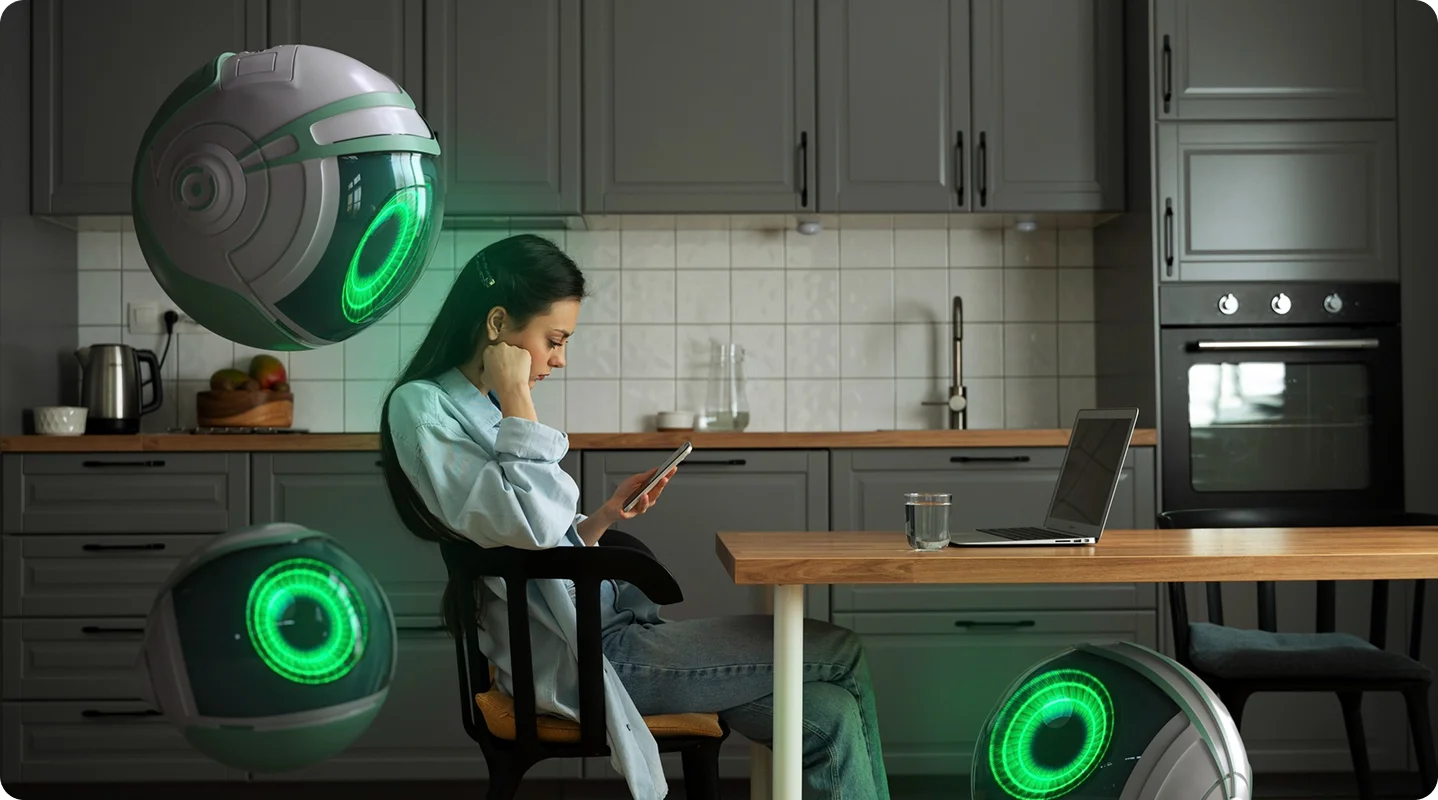 Woman working on a laptop at a kitchen table beside glowing green speakers