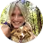 Smiling woman with long hair outdoors holding a small dog near her face.