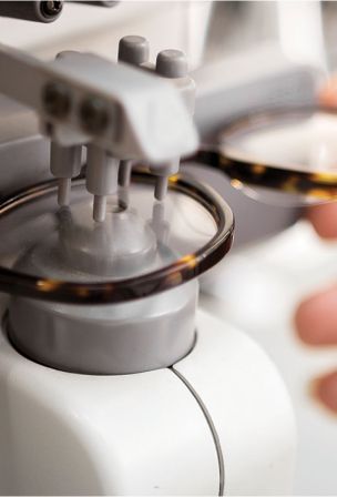Close-up of eyeglass lenses being mounted or adjusted by precision machinery.