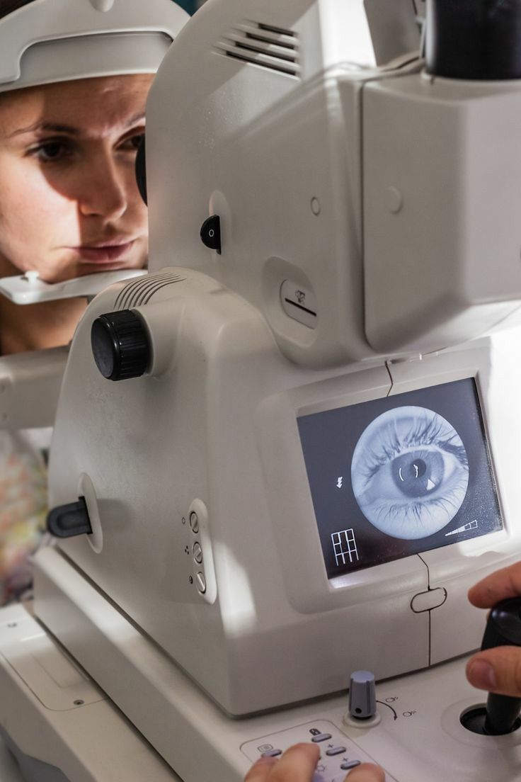 Person undergoing an eye exam using a retinal imaging device showing a close-up of an eye on the screen.