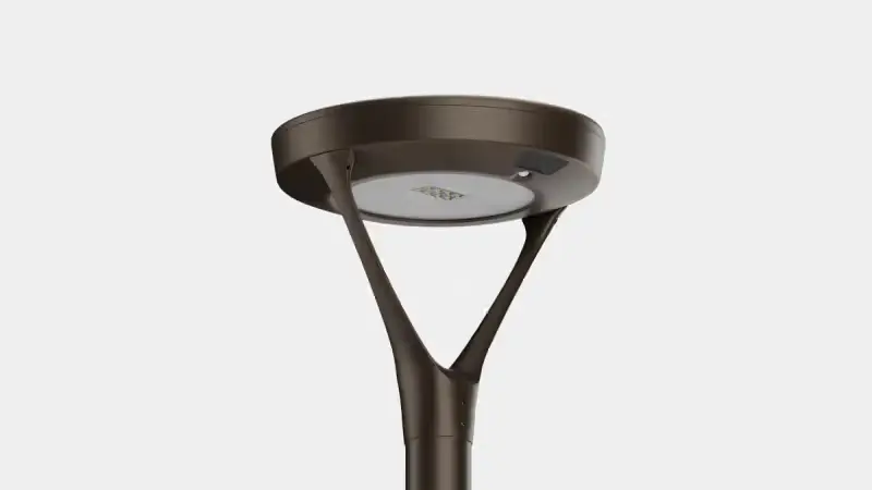 Modern outdoor street lamp with a round light fixture and Y-shaped support on a pole against a light background.