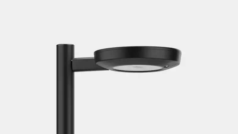 Modern black outdoor street lamp with a round flat light head mounted on a vertical pole.