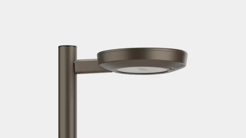 Modern street lamp with a round flat light fixture mounted on a vertical pole against a white background.