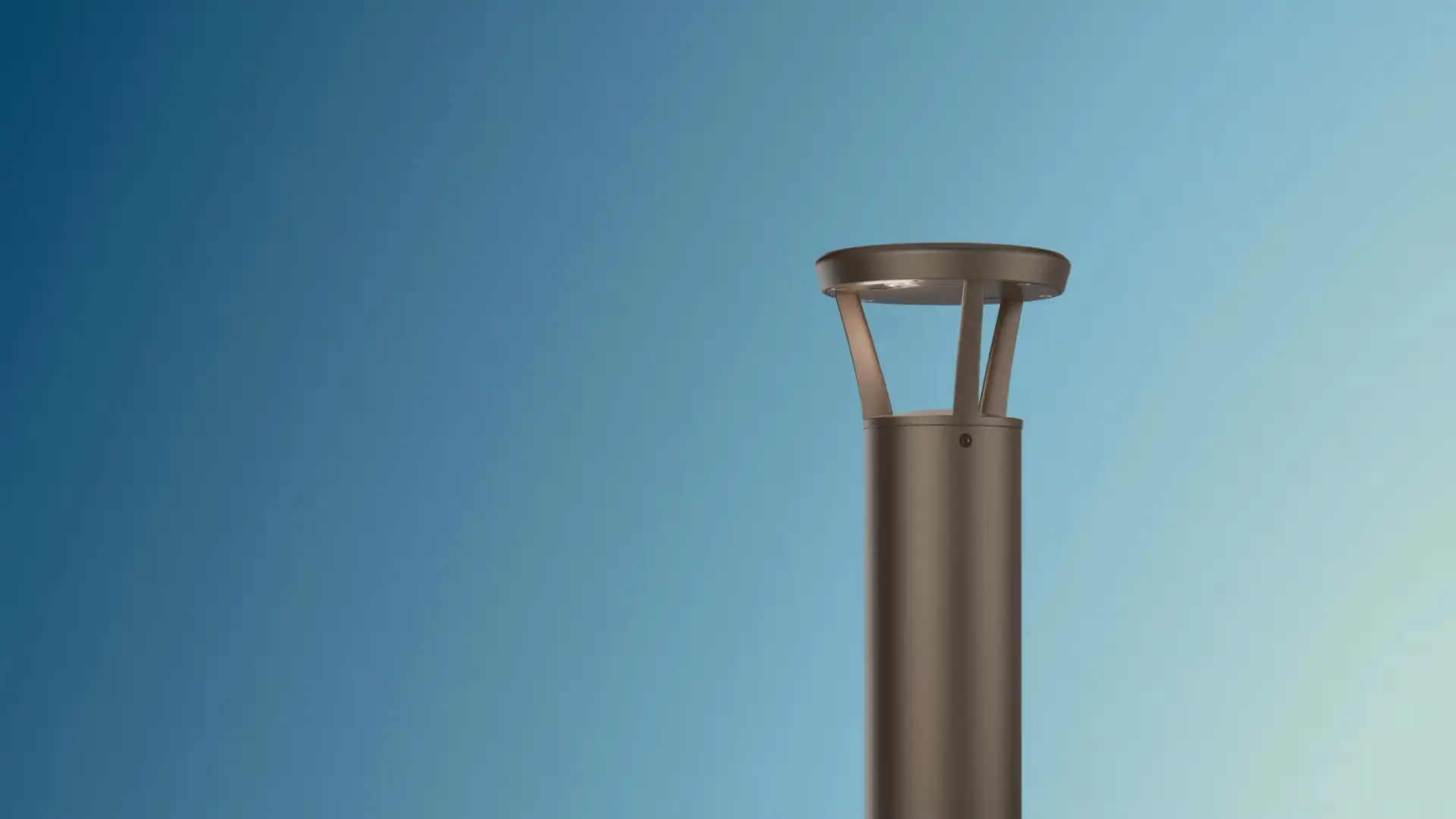 Modern metallic outdoor bollard light against a clear blue sky.