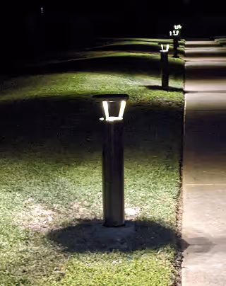 Outdoor pathway lit by a row of short modern garden lights at night.