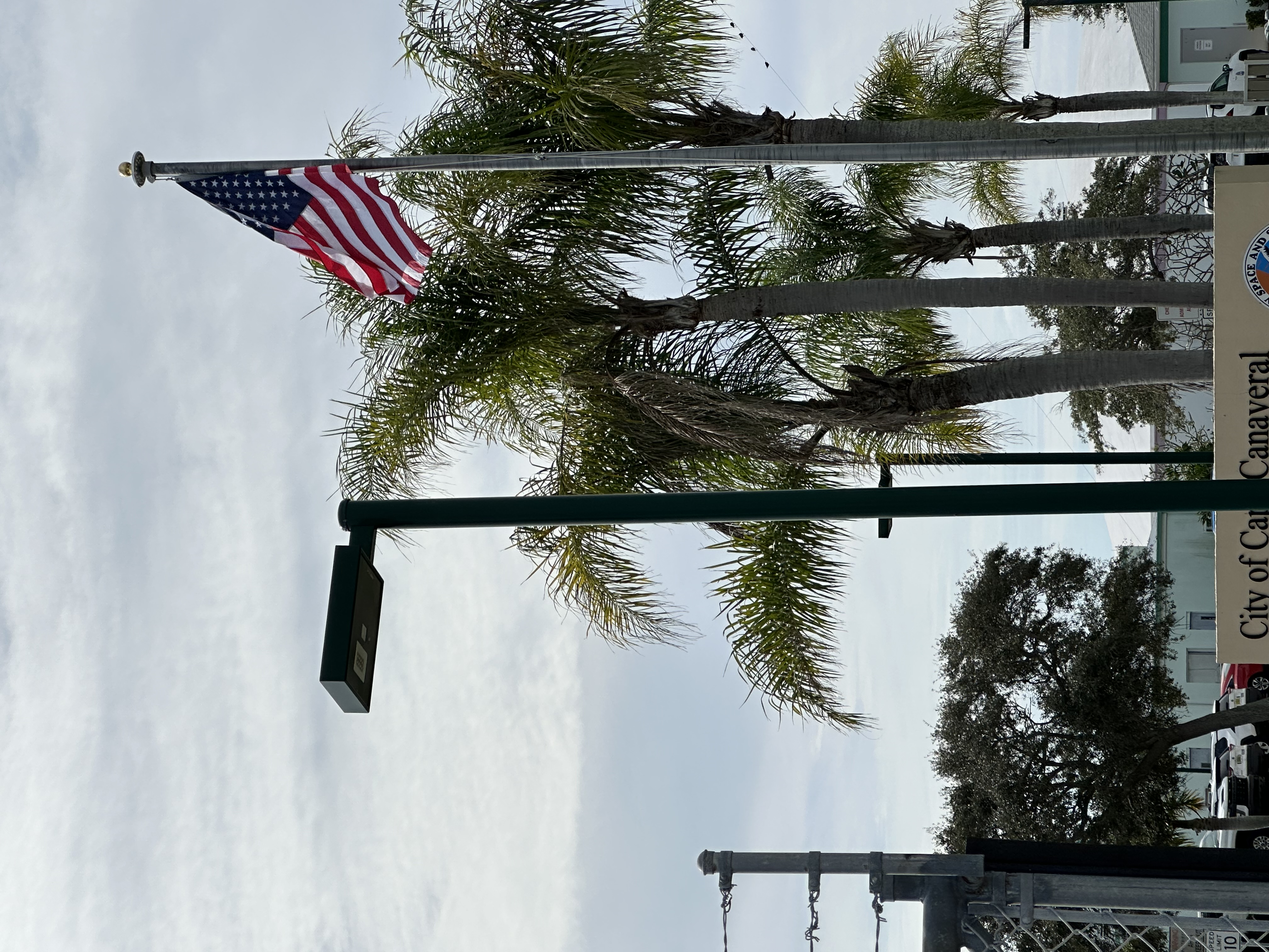 Wooden pole with solar panel and light fixture against blue sky near Nordic Center building.