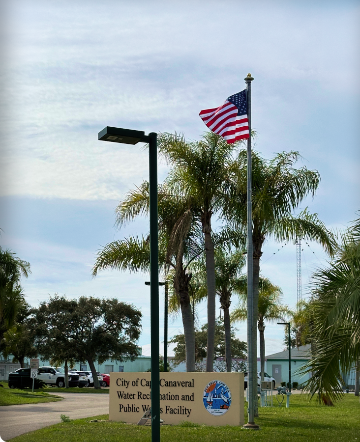 Wooden pole with solar panel and light fixture against blue sky near Nordic Center building.