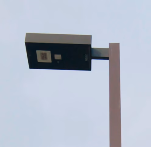 Close-up of a modern rectangular street lamp against a clear sky.