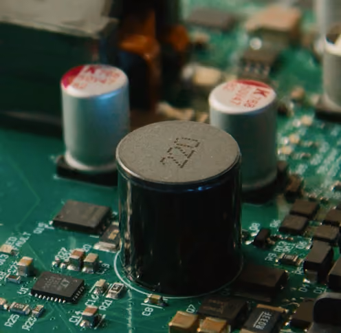 Close-up of capacitors and chips on a green electronic circuit board.