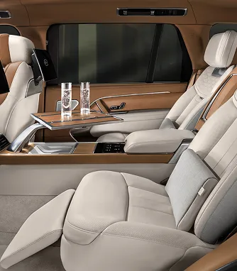 The cream leather rear cabin of a luxury car with a folding table and water glasses