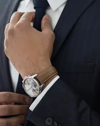 A man in a pinstripe suit adjusting his cuff, a wristwatch on his wrist
