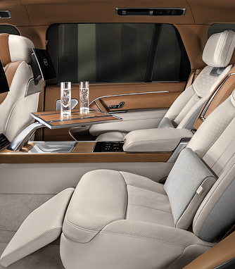 The cream leather rear cabin of a luxury car with a folding table and water glasses