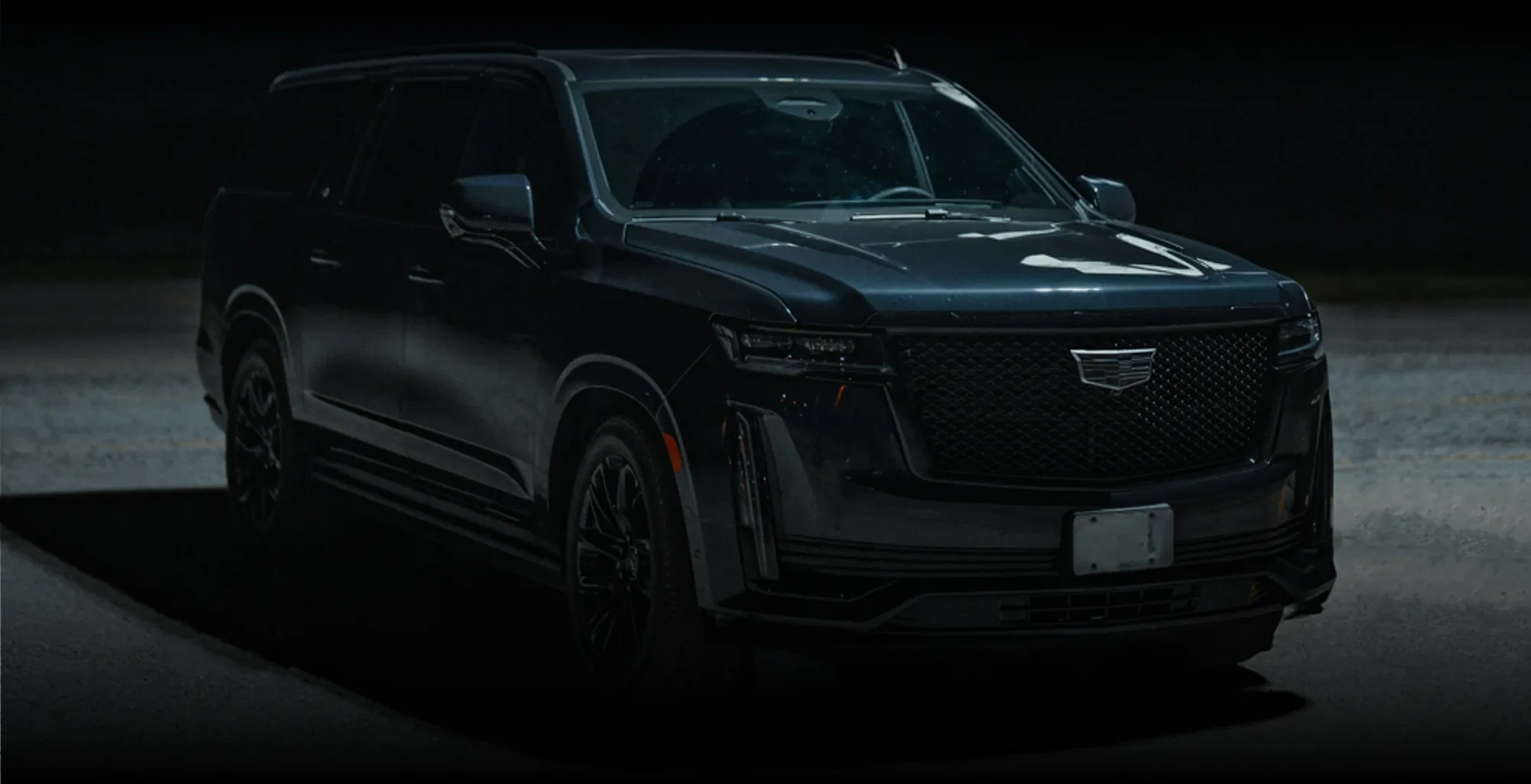 A black Cadillac Escalade parked at night