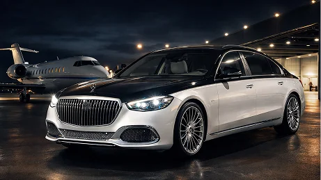 A silver Mercedes-Maybach sedan parked beside a private jet in a hangar