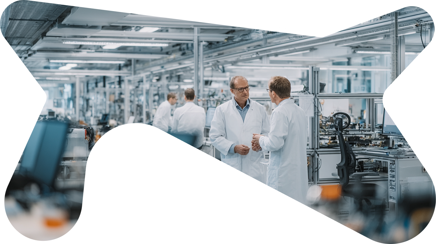 Two scientists in white lab coats talking in a high-tech industrial lab environment.