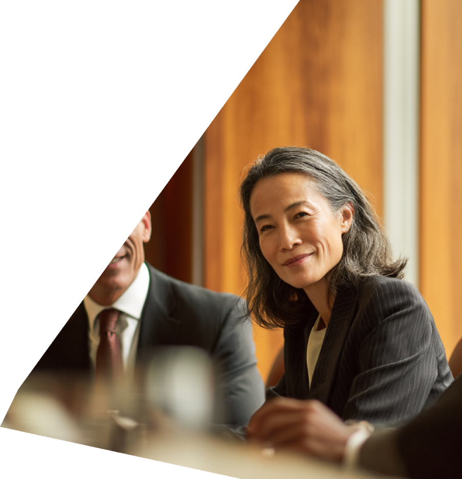 Smiling businesswoman in pinstripe suit at a meeting with colleagues.