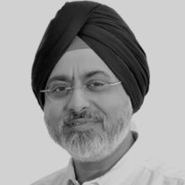 Man wearing a black turban and glasses smiling with a grey beard and white shirt.