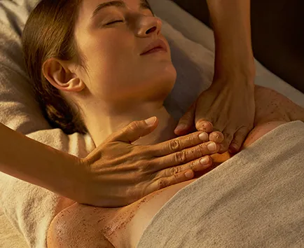 Femme recevant un massage relaxant avec un gommage au corps sur la poitrine.