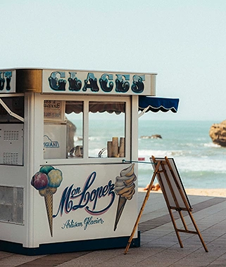 Kiosque à glaces avec illustrations de cornets et machine à glace au bord de la mer.