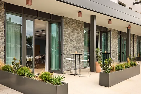 Facade of a building with large sliding glass doors and modern planters.