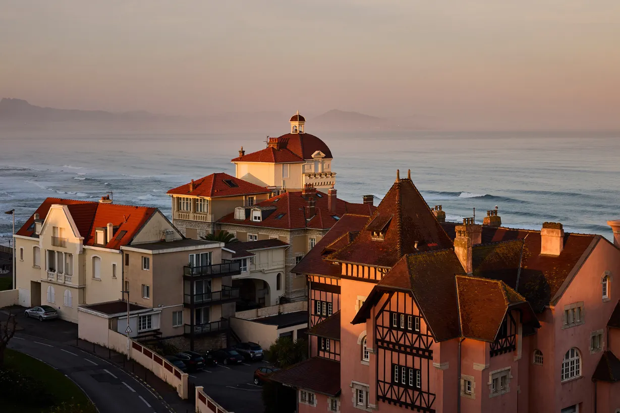 Maisons historiques au bord de la mer au coucher du soleil sous un ciel clair.
