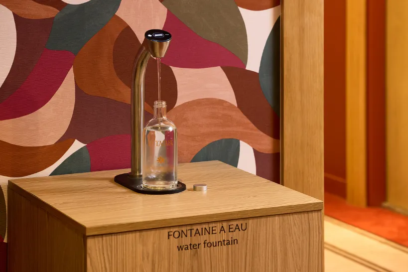 Fontaine à eau moderne distribuant de l'eau dans une bouteille en verre sur un meuble en bois.
