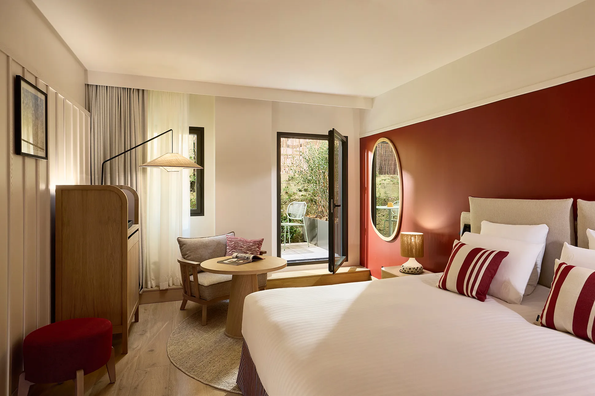 Chambre d'hôtel avec deux lits, mur terracotta et accès à une terrasse verdoyante